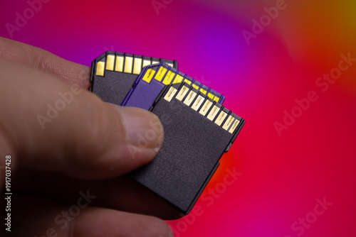 Bild auf Leinwand Holding multiple SD memory cards in a hand with a background of colorful light p