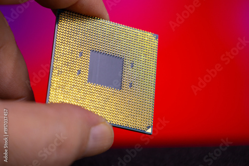 Photos Close view of a hand holding a computer microprocessor with a shiny gold surface