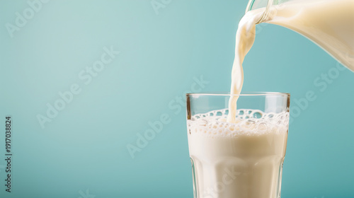 fresh milk pouring in a smooth stream into a clear glass, milk level rising with visible foam and round bubbles forming on the surface, crisp glass rim and reflections, minimal com