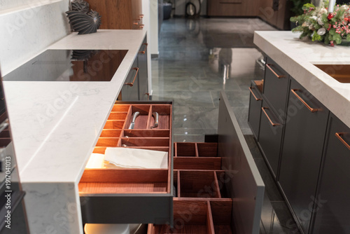 Open kitchen drawer with wooden organizer and lighting in luxury interior