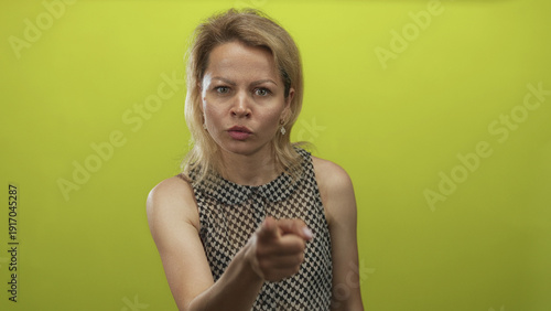 Canvastavla Woman pointing finger to camera in green studio with intense expression and direct stance; anger accusation