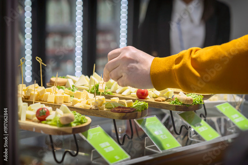 Cheese cubes served on wooden boards with toothpicks at food tasting counter in supermarket. Concept of food sampling, cheese tasting, retail promotion marketing