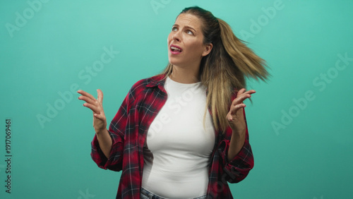 Woman in red plaid shirt raises palms in a shrugging gesture with expressive face in studio; exasperation doubt.