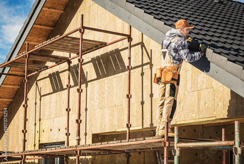 Фотография Worker Installs Roofing on a House Under Construction