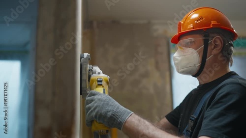 Construction worker smoothing a wall with an electric sander