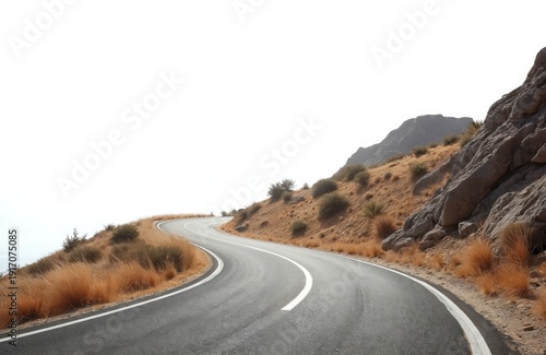 Winding asphalt road climbs dry rocky hillside. Arid landscape with sparse brush and brown grass under bright white sky. Offers sense of journey and freedom.