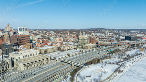 Aerial view of downtown Albany, New York in winter, featuring skyline, historic architecture, and snow-covered streets under clear sky.