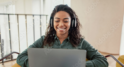 Bilde på lerret A woman with curly hair wears headphones and smiles while sitting at a laptop