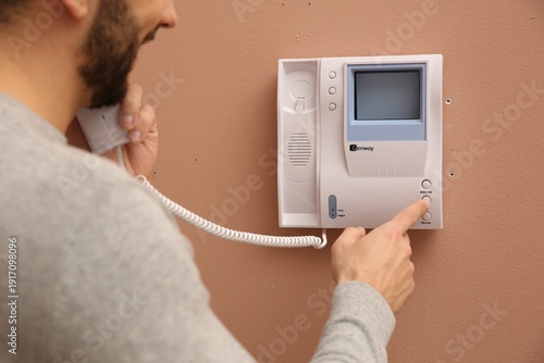Slika na platnu Man answering intercom call at home, closeup