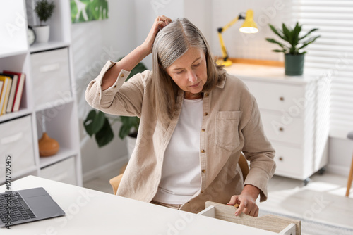 Amnesia. Senior woman trying to remember something at white table indoors