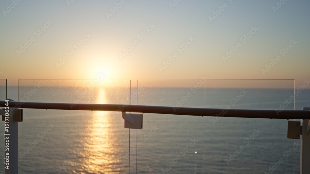 Obraz premium Glass balcony railing with defocused sunset over the ocean, soft bokeh outdoor; background backdrop copyspace template.