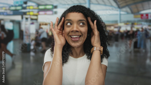 Free Download African american woman holding head with both hands in busy airport terminal amid blurred travelers; stress. - GFXLoad