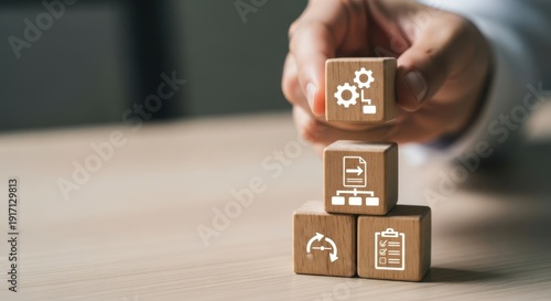 Workflow icons on wooden cubes set by hand with shallow depth and simple minimal desk background lightly blurred.