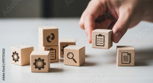 Workflow icons on wooden cubes set by hand with shallow depth and simple minimal desk background lightly blurred.