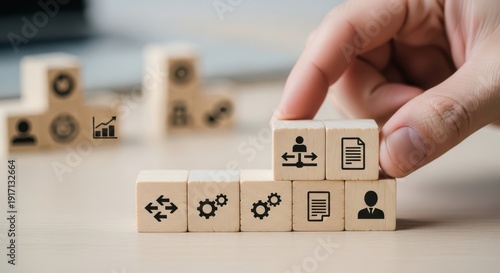 Workflow system icons on wooden cubes placed by hand using natural depth and minimalistic softly blurred surroundings.