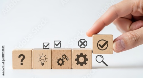 Decision making icons on wooden cubes being aligned by hand using cinematic shallow focus and white background blur effect.