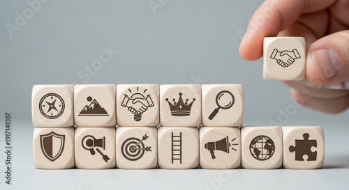 Leadership development symbols on wooden cubes placed by hand using fine shallow focus and neutral blurred background.