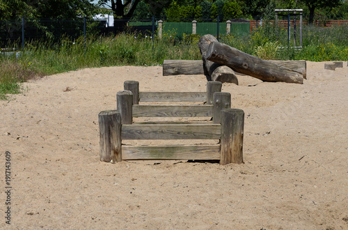 Wooden agility obstacles on sandy ground in dog park, outdoor training area for pet exercise and play, fenced canine playground for active lifestyle and responsible pet care