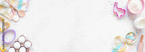 Easter or spring baking double border against a white marble banner background. Overhead view. Cookie cutters, eggs, and ingredients.