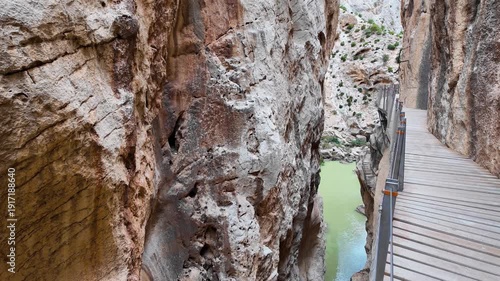 A thrilling Point of View shot capturing the walk along the narrow wooden boardwalk of Caminito del Rey, clinging to the vertical rock walls of the Gaitanes Gorge in Malaga.