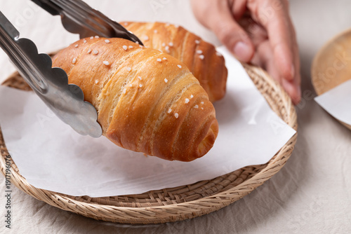 Fotografija Salt bread (Shio pan) with sea salt flakes is picking up by tongs, Japanese bake