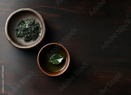 Top view of tea and leaf in small bowl on wooden table with copy space.