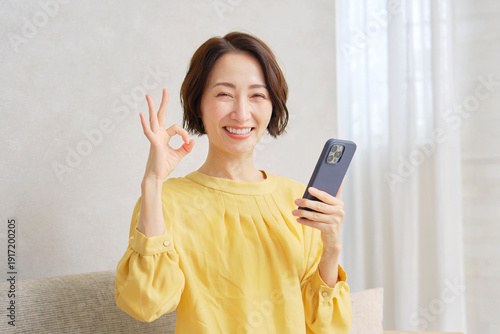 Wallpaper Mural リビングでOKサインをするスマホを持った女性 Torontodigital.ca