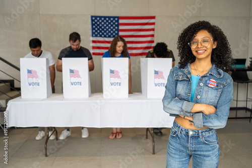 Fotografie young African American woman smiles wearing a 2026 vote pin button at a US election polling station