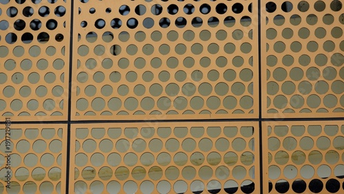 Obraz na plátne Close-up of an orange perforated metal screen with a repetitive circular pattern