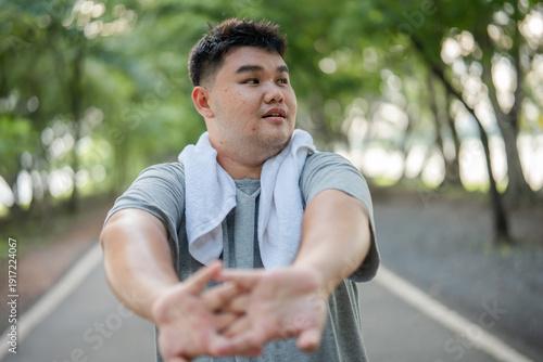 Asian plus-size man stretching body and exercise outdoors in garden. 