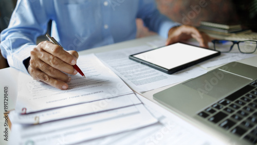 close up shot, asian businessman reviewing document using tablet and laptop working. professional lawyer reading and checking business documents and contract