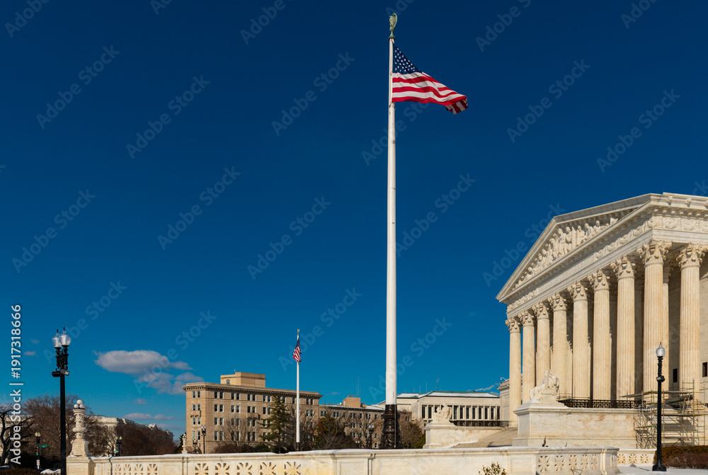 Naklejka premium American flag flying above supreme court architecture. Judicial branch concept with historic neoclassical building. Democracy and legal system symbol in capital city.