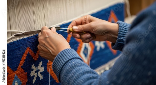 Person skillfully stitching a vibrant blue and orange patterned rug with precision and care