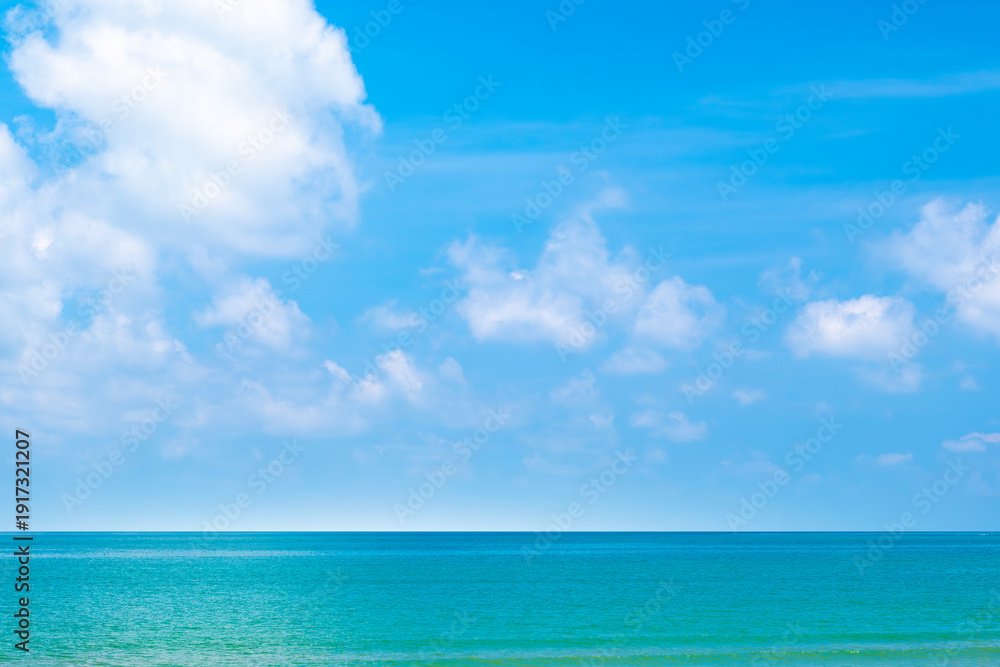 Obraz premium Tropical Nature clear sky and summer sea water under a clear blue sky with beautiful clouds and bright sunlight. Perfect for summer vacation and travel background