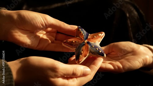 Human Hands Carefully Holding Small Orange Monarch Butterfly Against Dark Background with Dramatic Lighting