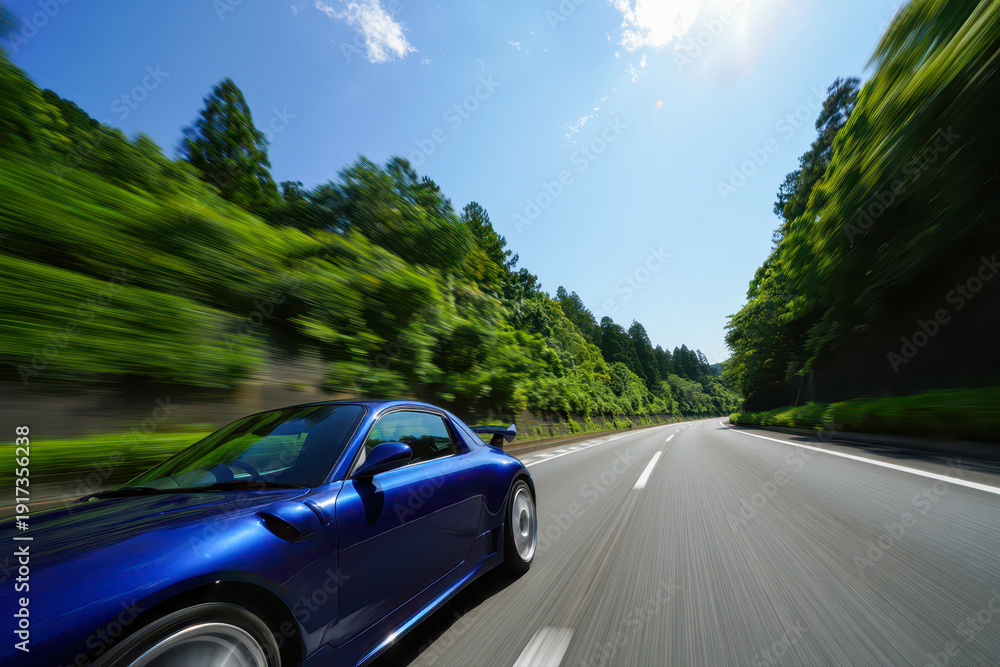Naklejka premium A sleek sports car cruising along a scenic, tree-lined highway on a bright day