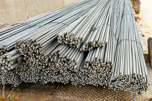 Steel reinforcement bars stacked on construction site, showcasing their ribbed texture and metallic sheen. These bars are essential for providing strength and stability in concrete structures
