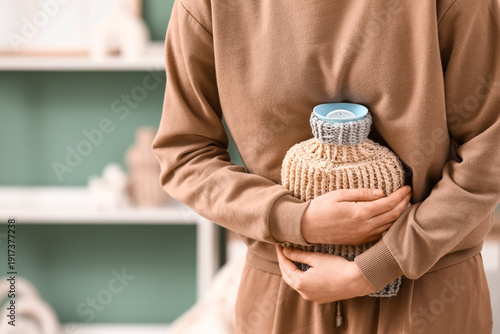 Canvas Print Woman warming her belly with hot water bottle at home