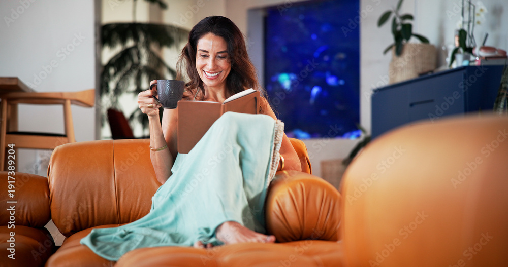© EineroLens25/peopleimages.com - Coffee, reading book and woman on sofa in home for hobby, relax and literature for learning. Happy, house and person with drink and novel, story or fiction for peace, calm and literacy in living room © EineroLens25/peopleimages.com - Coffee, reading book and woman on sofa in home for hobby, relax and literature for learning. Happy, house and person with drink and novel, story or fiction for peace, calm and literacy in living room