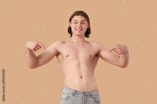 Young man pointing at himself on beige background. Body positive concept