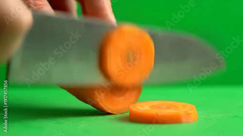 Wallpaper Mural A chef's knife expertly cuts a vibrant orange carrot into uniform round slices on a bright green surface. Torontodigital.ca