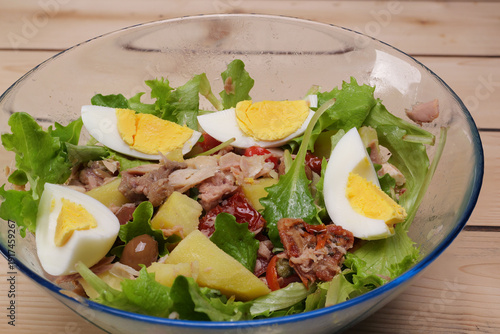 Ciotola con insalata di lattuga, pomodori, tonno, olive, patate, capperi 