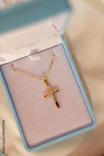 Gold cross necklace displayed in blue jewelry box with soft lining on a light surface
