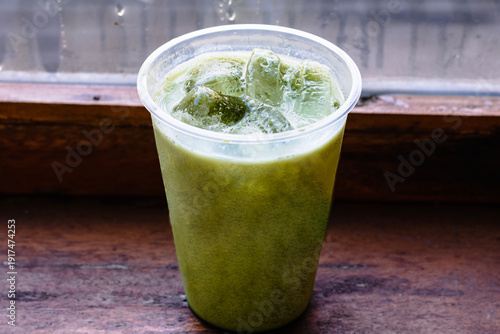 Iced Matcha or Green Tea in Plastic Glass, High Angle View. Wooden table and place for text.table and place for text.