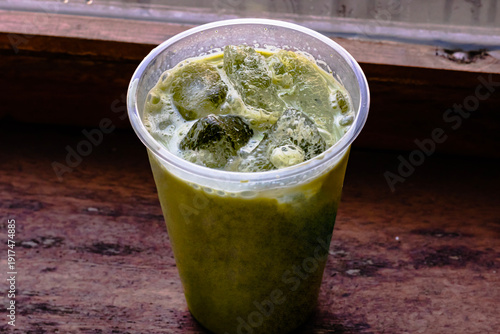 Iced Matcha or Green Tea in Plastic Glass, High Angle View. Wooden table and place for text.table and place for text.