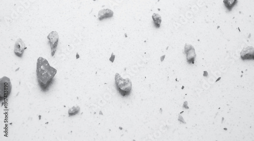 Close up of small grey pebbles scattered on a white textured surface