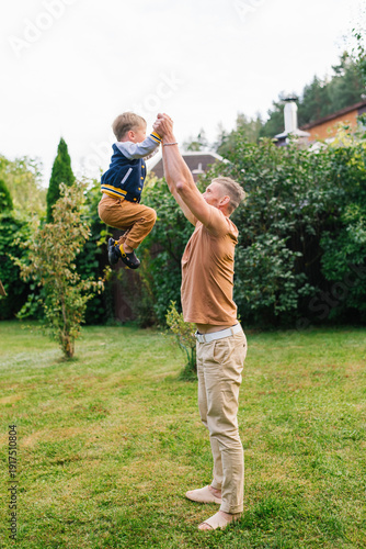 Father Lifting His Son In Green Garden