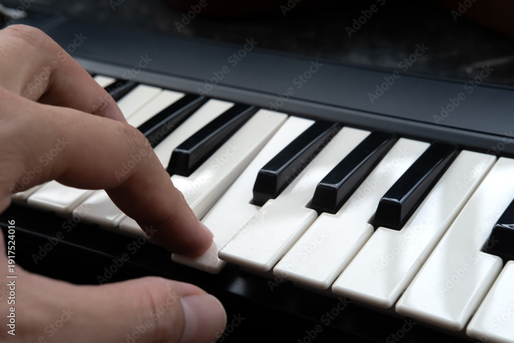 Fototapeta premium Close Up of Hand Playing Piano Keyboard, Music Practice and Learning Concept.