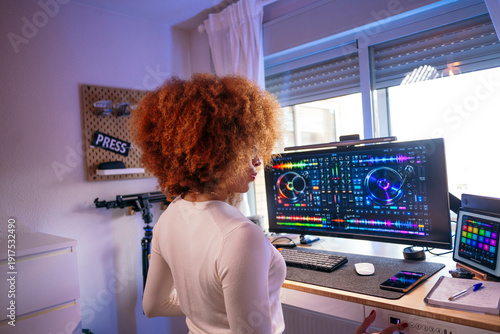 Woman producing music using digital audio workstation at home