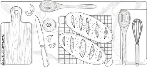 Overhead view of baking ingredients and tools including two loaves of bread, garlic, a knife, and utensils
